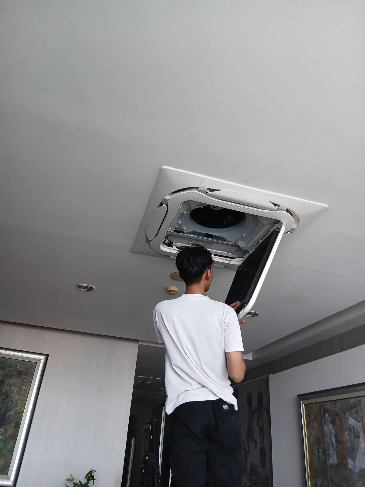 Teknisi MJE membersihkan unit AC cassette di plafon
